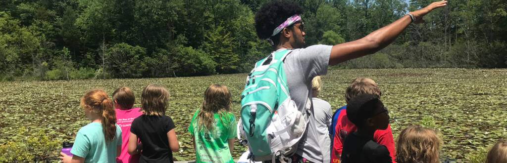 group of youth with counselor learning about the pond enviornment