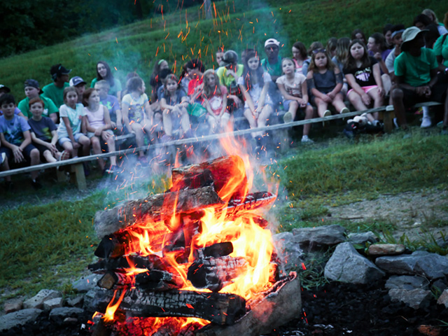 Campfire area with seating and a stage. This area is right in front of the lake.