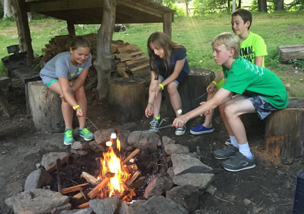 Group of youth making smores over a campfire