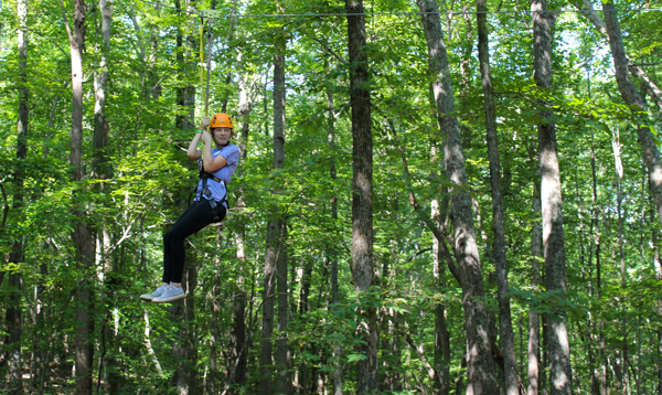 A child flying through the trees on the high ropes course.
