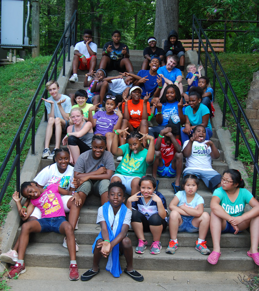 Group of children making goofy faces on a set of stairs outside.