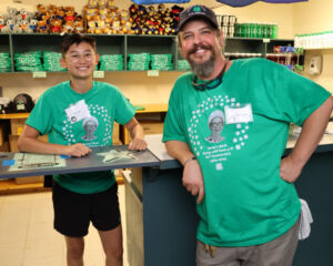 2 people with Betsy's bash shirts on, standing in the camp store