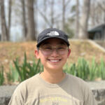 an outside photo of summer camp director zoe tate wearing a hat and smiling