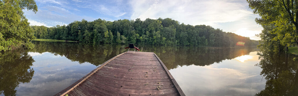 dock at the lake with the sky and trees on a sunny day