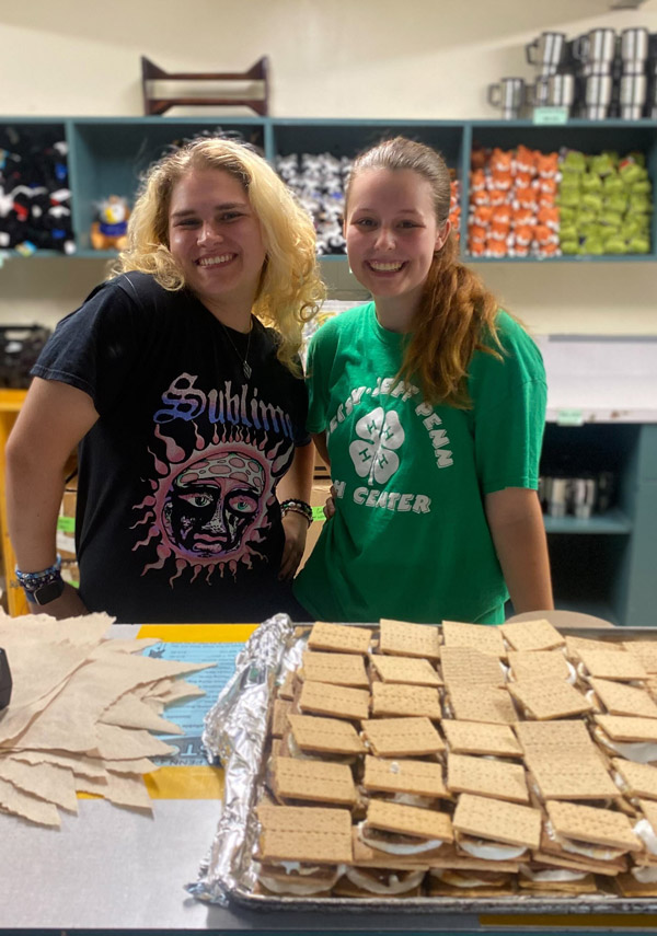 2 counselors handing out smores in the camp store