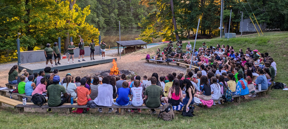 group around the campfire watching counselors put on a show