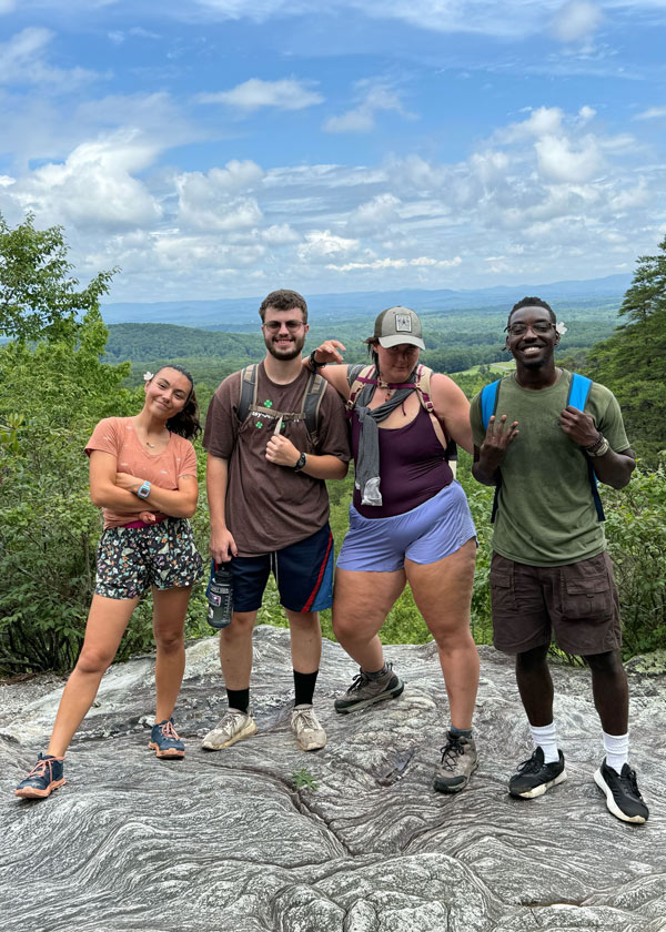 group of counselors on a hiking trip standing on rock overlooking mountains