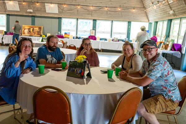 group sitting at round table by auction tables