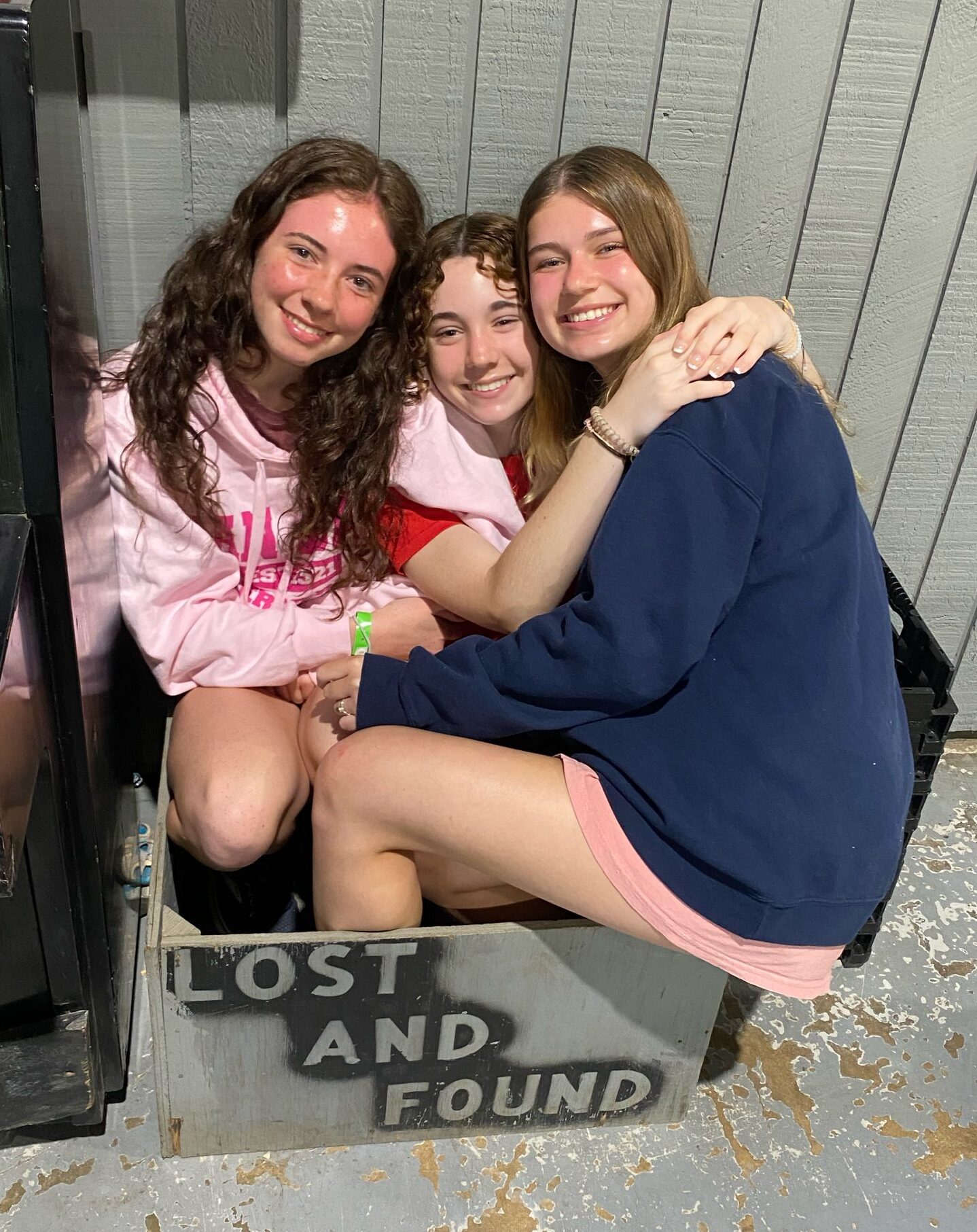 Three girls sitting in the lost and found box