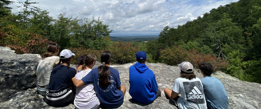 Eight children sitting on a rock overlooking the view from Pilot Mountain.